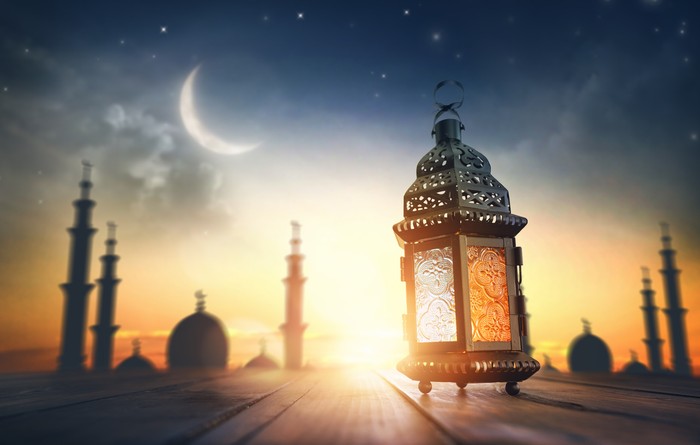 Ornamental Arabic lantern with burning candle glowing at night. Festive greeting card, invitation for Muslim holy month Ramadan Kareem.