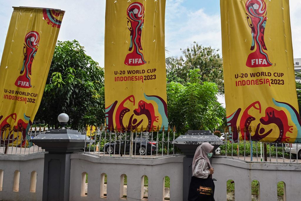 Seorang wanita berjalan melewati spanduk untuk turnamen sepak bola Piala Dunia FIFA U-20 Indonesia 2023 di Jakarta pada 30 Maret 2023. - FIFA mengumumkan pada 29 Maret telah menghapus Indonesia sebagai tuan rumah Piala Dunia U-20 tahun ini di tengah kekacauan politik atas Israel partisipasi. (ADEK BERRY/AFP via Getty Images)