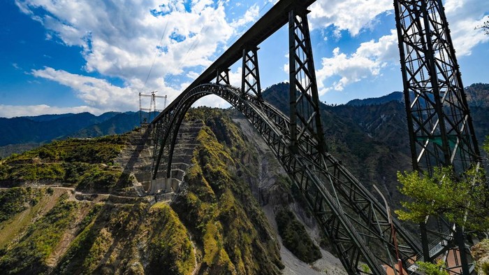 Wujud Jembatan Rel Kereta Tertinggi di Dunia, Ada di India Lho KATRA, INDIA - MARCH 26: A view of newly constructed Chenab Bridge, World's highest Rail arch bridge of Indian Railways on Udampur- Srinagar-Baramulla-Rail link project during its media preview in Reasi district, on March 26, 2023 in Katra, India. The bridge is supported by 96 cables, making it stronger and suitable for trains running at speeds of up to 100 kmph, a senior officer of northern railways was quoted as saying in a report. (Photo by Sanchit Khanna/Hindustan Times via Getty Images)