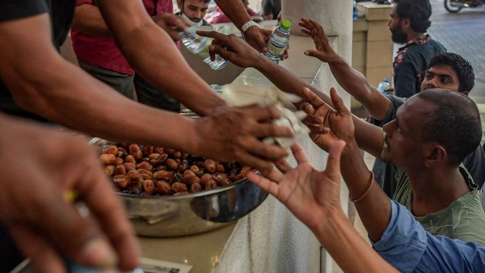 In this picture taken on April 4, 2022, people distribute dates and water bottles to Muslim devotees to break their fast during the holy month of Ramadan in Male. (Photo by Mohamed Afrah / AFP) (Photo by MOHAMED AFRAH/AFP via Getty Images)