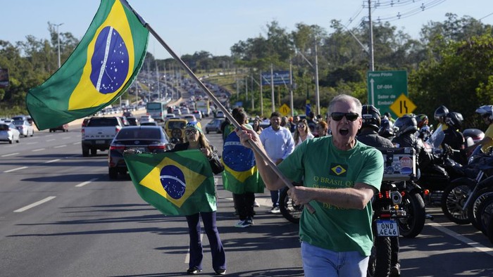 Mantan Presiden Jair Bolsonaro Kembali ke Brasil, Disambut Simpatisan Brazil's former President Jair Bolsonaro waves to supporters at the Liberal Party's headquarters in Brasilia, Brazil, Thursday, March 30, 2023. Bolsonaro arrived back in Brazil on Thursday after a three-month stay in Florida, seeking a new role on the political scene. (AP Photo/Eraldo Peres)