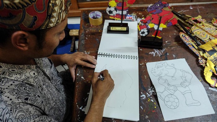 PERAJIN SOUVENIR PIALA DUNIA U-20 GAGAL PRODUKSI Perajin wayang kulit Margono menggambar pola wayang berkarakter maskot Piala Dunia U-20 Bacuya untuk souvenir di sentra Industri Kecil Menengah (IKM) Semanggi Harmoni, Solo, Jawa Tengah, Kamis (30/3/2023). Margono kecewa dengan batalnya pelaksanaan Piala Dunia U-20 di Indonesia karena produk souvenir yang akan dibuatnya gagal diproduksi. ANTARAFOTO/Maulana Surya/rwa.