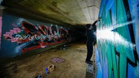 Seorang seniman grafiti, Ivan, melukis karyanya di sebuah terowongan Browns di Beeston, Inggris, Kamis (30/3/2023).