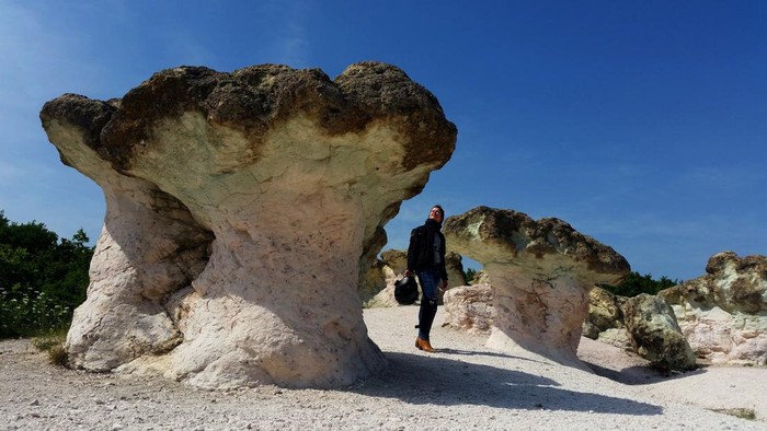 Uniknya Batu Jamur di Bulgaria yang Menarik Perhatian Visitors attend in front of The stone mushrooms rock formations, located near the village of Beli Plast, south east of the Bulgarian capital Sofia.The rock formations have the shape of natural mushrooms - their stalks are pink, and the caps are green. The height of the mushroom stalks and the width of the caps are up to 2.5 meters. They are made of rhyolite volcanic tuffs, which are the result of intensive underwater volcanic activity, dating back to the Paleocene. After the sea withdrawal and the consistent seabed rising, the influence of the erosion became visible. The rock formation is one of the most famous tourist attraction in Bulgaria. (Photo by /Sky Pictures Bulgaria/NurPhoto via Getty Images)