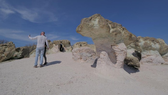 Visitors attend in front of The stone mushrooms rock formations, located near the village of Beli Plast, south east of the Bulgarian capital Sofia.The rock formations have the shape of natural mushrooms - their stalks are pink, and the caps are green. The height of the mushroom stalks and the width of the caps are up to 2.5 meters. They are made of rhyolite volcanic tuffs, which are the result of intensive underwater volcanic activity, dating back to the Paleocene. After the sea withdrawal and the consistent seabed rising, the influence of the erosion became visible. The rock formation is one of the most famous tourist attraction in Bulgaria. (Photo by /Sky Pictures Bulgaria/NurPhoto via Getty Images)