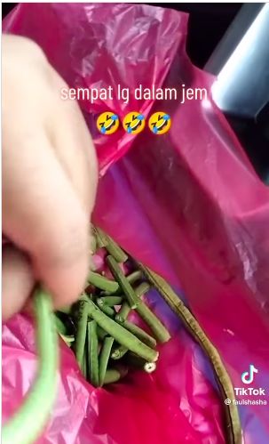 Wanita nyambi potong kacang panjang saat tejebak macet