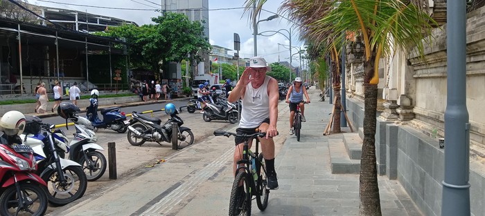 Turis asing bersepeda di trotoar Pantai Kuta, Sabtu (1/4/2023).