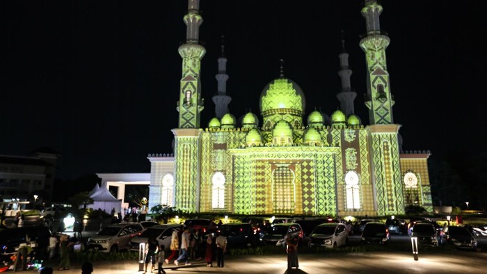 Pengunjung berswafoto dengan latar belakang video mapping yang ditampilkan saat acara Khazanah Fest di Masjid At-Thohir, Depok, Jawa Barat, Minggu (2/4/2023). Masjid At-Thohir yang dibangun sejak tahun 2022 dengan gaya arsitektur klasik modern tersebut menampilkan pertunjukkan video mapping nuansa Ramadhan. ANTARA FOTO/Asprilla Dwi Adha/YU