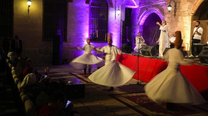 Menyaksikan Tari Sufi, Tarian Religius Penuh Makna Amr el-Toney, at top center, founder of the Mawlawiyah dervish dance troupe, directs dervishes from the Al-Tannoura Egyptian Heritage Dance Troupe, during a religious performance to mark the holy month of Ramadan at the ancient Prince Taz palace in Cairo, Egypt, Wednesday, March 29, 2023. Muslims throughout the world are celebrating Ramadan, the holiest month in the Islamic calendar, refraining from eating, drinking, smoking and sex from sunrise to sunset. (AP Photo/Amr Nabil)