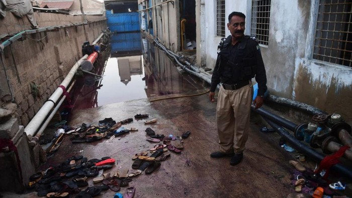 A police officer stands next to the footwear of victims following a stampede that ocurred during a Ramadan alms distribution for people in need, in Karachi on March 31, 2023. - At least nine people were killed in a crowd crush in Pakistan's southern city of Karachi on March 31 as a Ramadan alms donation sparked a stampede in the inflation-hit nation, officials said. (Photo by Asif HASSAN / AFP) (Photo by ASIF HASSAN/AFP via Getty Images)