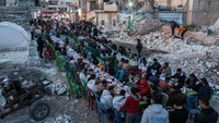 Di antara gundukan dan puing-puing bangunan yang hancur akibat gempa M 7,8, warga menikmati hidangan berbuka puasa Ramadan bersama. 
