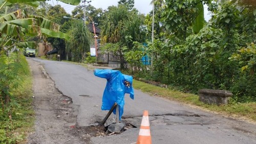 Ruas jalan Ban-Pempatan yang rusak di beberapa titik dipasangi orang-orangan sawah oleh warga Desa Ban, Karangasem agar tidak menimbulkan kecelakaan. (istimewa)
