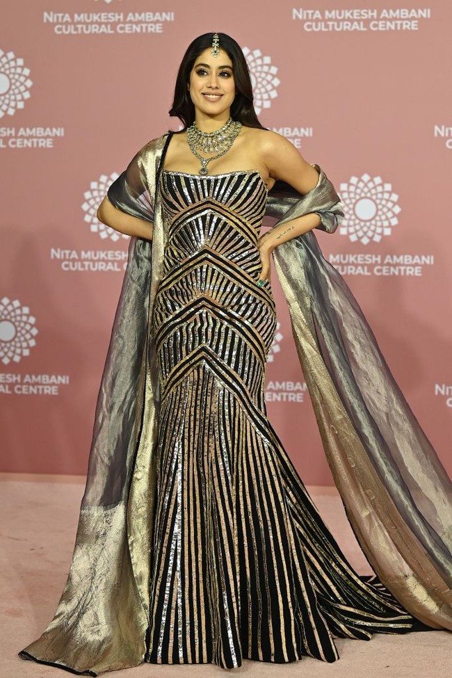 Anak mendiang aktris legendaris Sridevi, Janhvi Kapoor, tak ketinggalan bergaya glamor dengan gaun mermaid beraksen sulur hitam-silver. Foto: Getty Images