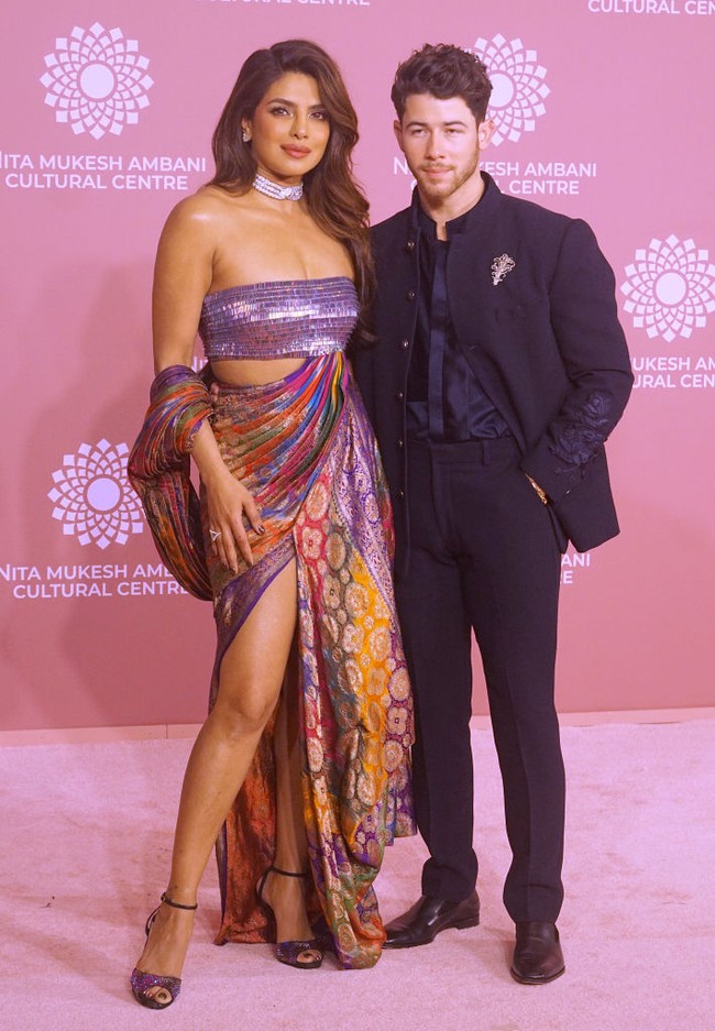 Priyanka Chopra hadir ditemani Nick Jonas. Aktris Bollywood ini tampil seksi dengan sari berhias benang emas. Dia memadukan kain sari bersama crop top silver metalik yang menambah kesan glamor. Foto: Getty Images