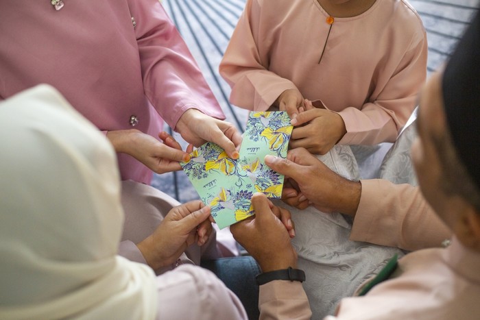 Young kids receiving gift money from parents as part of the Islamic celebration of Hari Raya Aidilfitri (Eid al-Fitr)