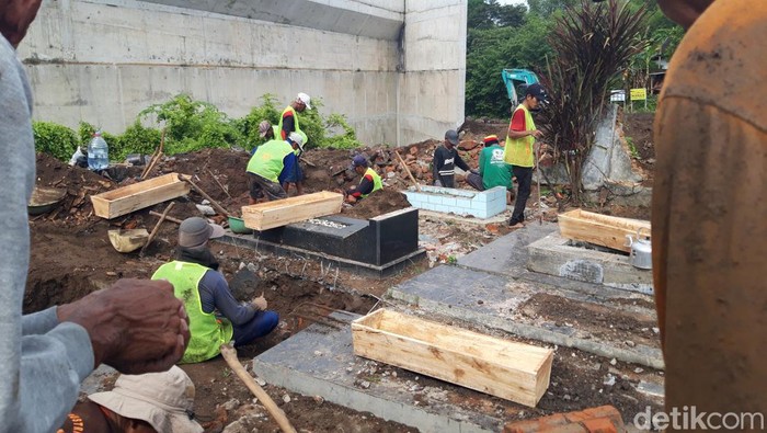 Petugas menggali makam yang kena jalan tol Jogja-Solo di Kateguhan, Sawit, Boyolali untuk dipindahkan ke lokasi baru, Senin (3/4/2023).