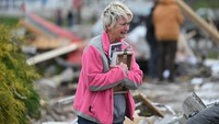 Debbie Lowdermilk memegang foto dan menangis saat ia melihat sekolah miliknya yang hancur sehari setelah tornado menghantam Sullivan, Indiana, AS, 1 April 2023. REUTERS/Jon Cherry.