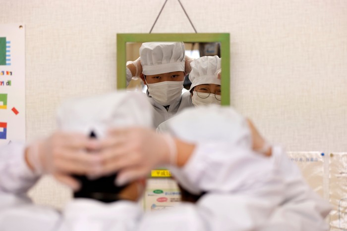 Eita Sato (first on the left), 15, and Aoi Hoshi (first on the right), 15, the only two students at Yumoto Junior High School, have their last school lunch with their teachers before their graduation and the institution's closing ceremony, Fukushima Prefecture, Japan, March 9, 2023. Eita and Aoi, who have been together since three, are the last two graduates of Yumoto Junior High, a public school established in 1947 that in its prosperous years sent out more than 50 graduates, but with only a few of enrolments expected in the coming years, the village decided to close the school for good. 
