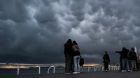 Orang-orang memotret awan mammatus di sepanjang pantai Mediterania Nice, Prancis, Senin (3/4/2023).  