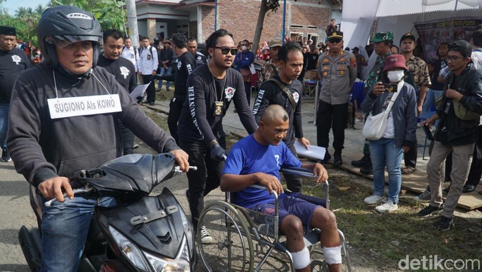 Pelaku perampokan bersenjata api didorong menggunakan kursi roda saat akan menjalani rekonstruksi di Desa Kaliwungu, Kecamatan Kedungreja, Kabupaten Cilacap, Senin (4/4/2023).