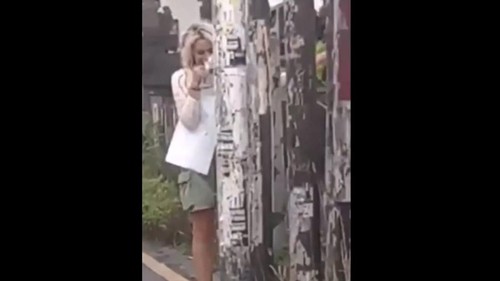Tangkapan layar video viral bule perempuan di Canggu pasang poster liar di tiang listrik. (IST)