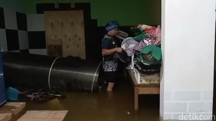 Warga saat mengemasi barang berharga saat rumahnya dilanda banjir.