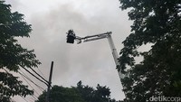 Petugas pemadam menggunakan kendaraan skylift berupaya menjangkau api pokok dari ketinggian. Api di Apotek Kimia Farma Diponegoro itu berhasil dipadamkan pukul 13.41 WIB. (Foto: Deny Prastyo Utomo/detikJatim)