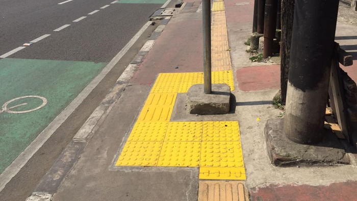 Guiding block yang sebelumnya terhalang papan bus stop  di depan Universitas Pratiwi, Jl Dewi Sartika, Jakarta Timur, sudah diperbaiki.
