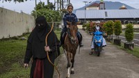 Seorang santi berjalan di depan seekor kuda saat mereka bersiap untuk mengikuti latihan memanah di pondok pesantren Al-Fatah Temboro, Magetan, Jawa Timur, Senin (3/4/2023).  