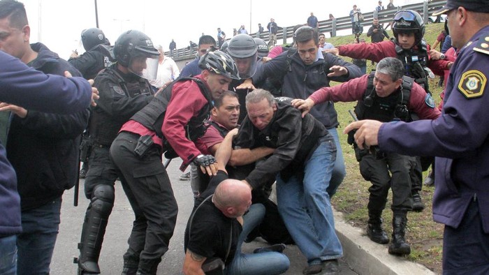 Sergio Berni, the security minister for the Buenos Aires province, center, is extracted from a protest in Buenos Aires, Monday, April 3, 2023. Berni was attacked during a protest by bus drivers after the murder of a co-worker while on the job. (AP Photo/Andres Pelozo)