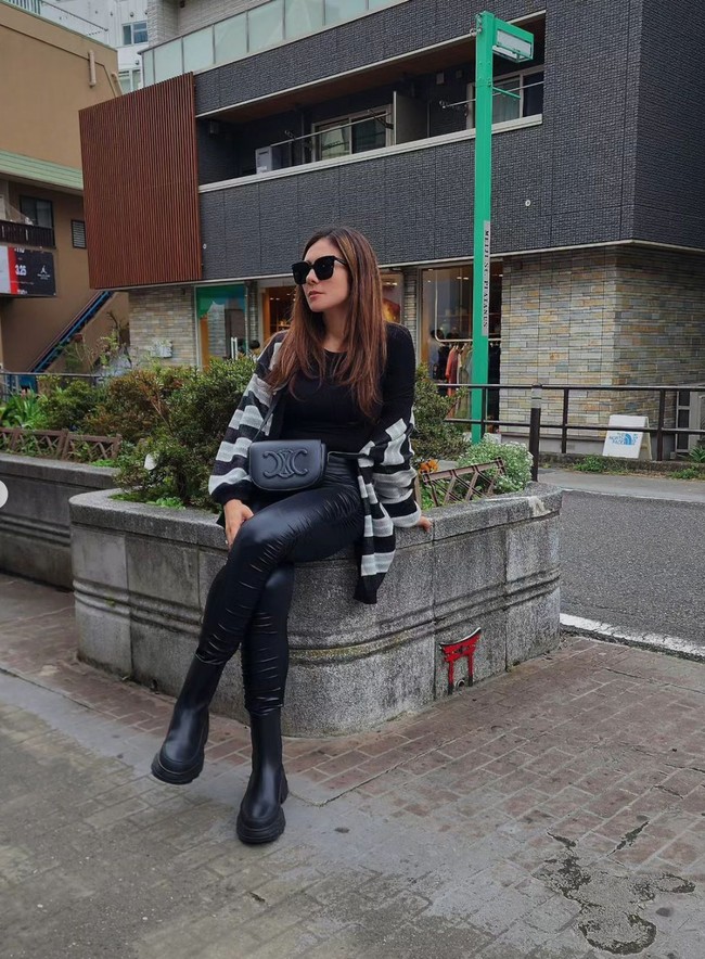 Tampil monokrom, Wulan memilih memadukan kaos lengan panjanag hitam dengan outer garis-garis dan celana panjang lateks. Agar semakin stylish, Wulan memilih mengenakan sepatu boots. Foto: Instagram/@wulanguritno