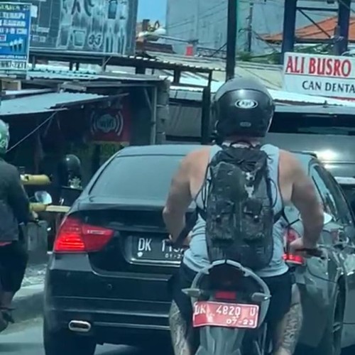Tangkapan layar seorang WNA mengendarai sepeda motor pelat merah nomor polisi DK 4820 U viral di media sosial.