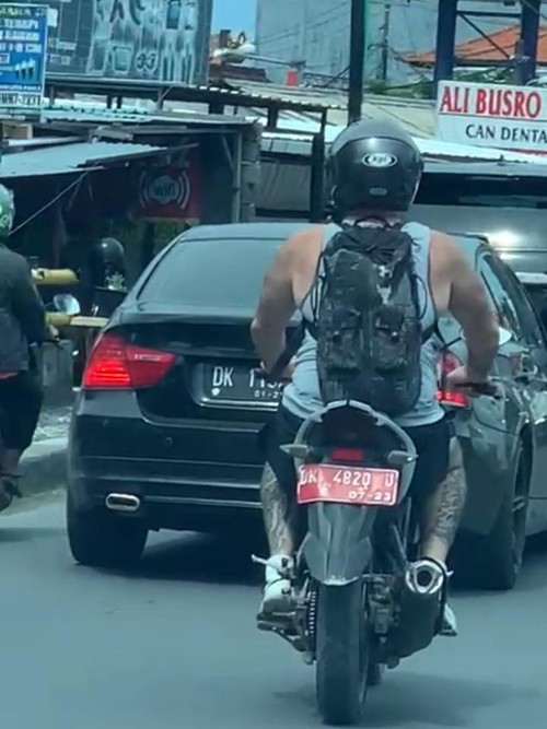 Tangkapan layar seorang WNA mengendarai sepeda motor pelat merah nomor polisi DK 4820 U viral di media sosial.