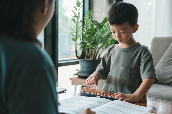 Asian mother teaching child ​boy Learning math with an abacus, education concept, home school, Social distancing, stay home, online learning class study math