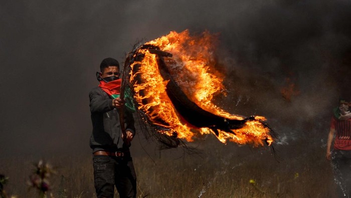A demonstrator covers his face with a Palestinian flag during a protest over tension in Jerusalem, at the Israel-Gaza border fence, east of Gaza City April 5, 2023. REUTERS/Mohammed Salem