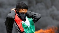 Seorang demonstran manjadikan bendera Palestina untuk menutupi wajahnya.