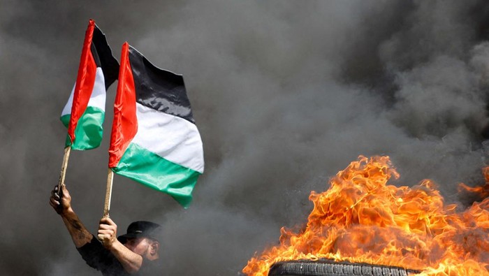 ISRAEL-PALESTINIANS/VIOLENCE-GAZA A demonstrator covers his face with a Palestinian flag during a protest over tension in Jerusalem, at the Israel-Gaza border fence, east of Gaza City April 5, 2023. REUTERS/Mohammed Salem