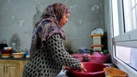 Samira Othmen mencuci piring menggunakan air yang dia kumpulkan dari sebuah sumur di Tunis, Tunisia, Minggu (2/4/2023).