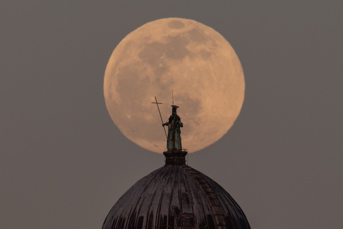 Full moon rises behind Saint Jean-Baptiste (San Giovanni Battista) statue over Baptistery in Pisa, Tuscany, Italy, on April 5, 2023. April full moon is also known as pink, egg and fish moon.  (Photo by Lorenzo Di Cola/NurPhoto via Getty Images)