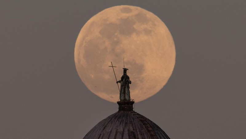 Full moon rises behind Saint Jean-Baptiste (San Giovanni Battista) statue over Baptistery in Pisa, Tuscany, Italy, on April 5, 2023. April full moon is also known as pink, egg and fish moon.  (Photo by Lorenzo Di Cola/NurPhoto via Getty Images)