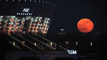 Bulan Purnama Merah Muda atau Pink Moon terlihat di dekat Stadion Nasional di Warsawa, Polandia, Rabu (5/4/2023). Menurut The Old Farmers Almanac, nama fenomena Pink Moon berasal dari mekarnya bunga phlox, yakni tanaman dengan bunga berwarna merah muda yang umumnya tumbuh di Amerika Utara. (STR/NurPhoto via Getty Images)  