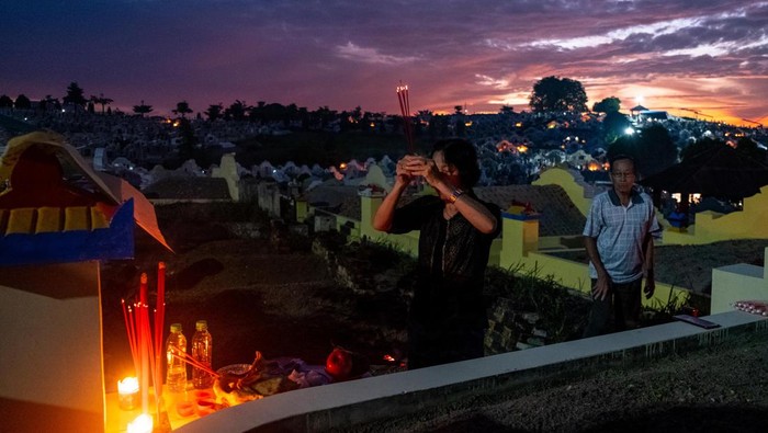 Potret Ziarah Makam Umat Konghuchu Saat Festival Qingming People pay respect to their relatives in front of a tombstone at Sentosa Cemetery to mark the Qingming Festival on April 5, 2023 in Pangkalpinang, Bangka Belitung Island, Indonesia. The Qingming Festival, falls on April 5, known as the ''Tomb Sweeping Day'', is a traditional time when Chinese people pay their respects to the deceased and ancestors, involving cleaning, repairing of tombs and sacrifice activities. (Photo by Resha Juhari/NurPhoto via Getty Images)