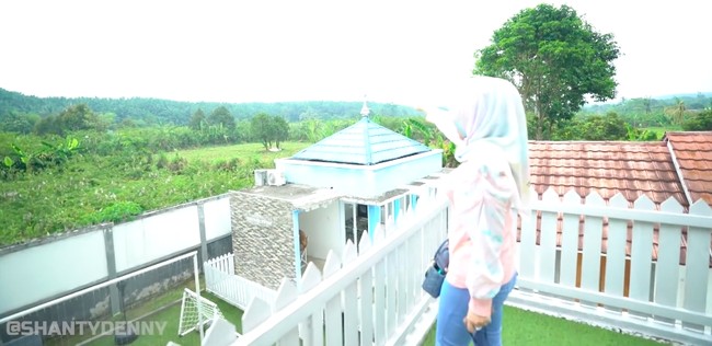 Adelia mengatakan rumah tersebut berdiri di atas lahan 6.000 meter persegi yang berada di tengah perkampungan. Meski lokasinya cukup jauh, mereka betah tinggal di sana karena pemandangan perbukitan dan hamparan hijau di sekitarnya.  (Foto: YouTube/Shanty Denny)