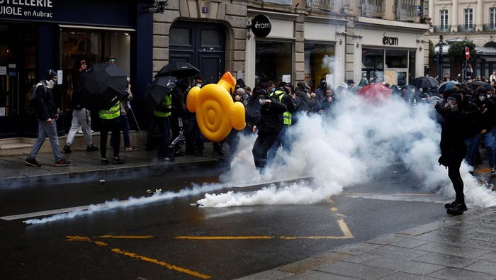 Aksi Tolak Reformasi Pensiun di Prancis Kembali Ricuh Masked protesters protect themselves with umbrellas near burning garbage bins amid clashes during a demonstration as part of the eleventh day of nationwide strikes and protests against French government's pension reform, in Rennes, France, April 6, 2023. REUTERS/Stephane Mahe