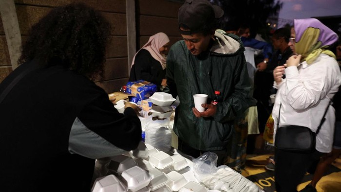 Thando Jansen and Romean September enjoy the hot meal they received during Iftar (breaking of the fast)  during the holy month of Ramadan at the site where Muslims and other organisations provide hot meals to the destitute and homeless in Cape Town, South Africa, April 6, 2023. REUTERS/Esa Alexander