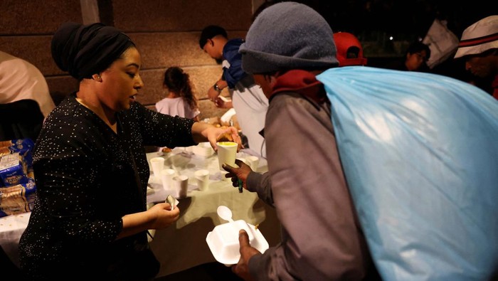 Muslim Afrika Selatan Isi Ramadan dengan Berbagi Thando Jansen and Romean September enjoy the hot meal they received during Iftar (breaking of the fast) during the holy month of Ramadan at the site where Muslims and other organisations provide hot meals to the destitute and homeless in Cape Town, South Africa, April 6, 2023. REUTERS/Esa Alexander