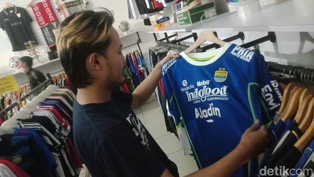Oktavian (30) memperlihatkan jersey Persib player issue dan supporter edition di tokonya di Cijerah