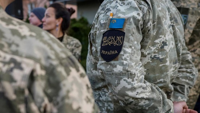 A Muslim soldier wears patches with the Shahada, an Islamic oath and the Flag of the Crimean Tatar people, as they attend an Iftar where Ukrainian President Volodymyr Zelenskiy will share a meal with Ukrainian Muslim soldiers, breaking their fast, during the holy fasting month of Ramadan, near a mosque in the outskirts of Kyiv, Ukraine, April 7, 2023. REUTERS/Alina Yarysh