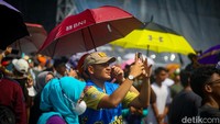 Warga tampak membawa payung untuk berlindung diri dari terik matahari. 