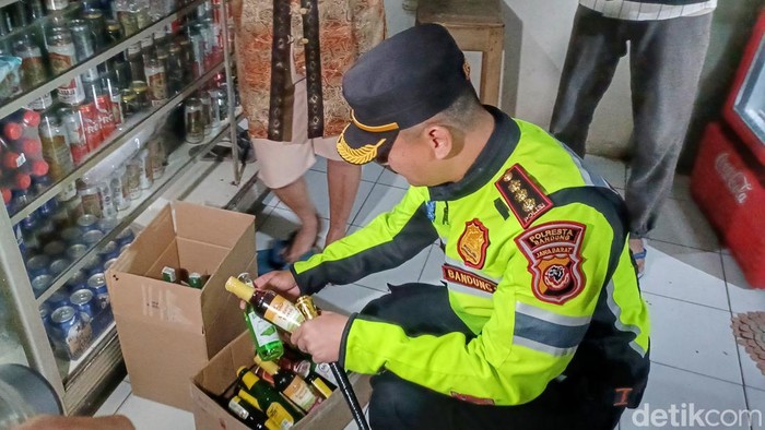 Polisi saat menemukan botol miras disembunyikan toko di Kabupaten Bandung, Minggu (9/4/2023).